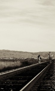 Two people walking along a railway track