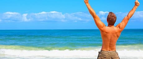 Traveller with arms raised facing the sea