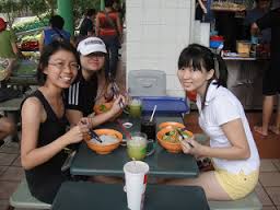Three young women eating at a street food stall